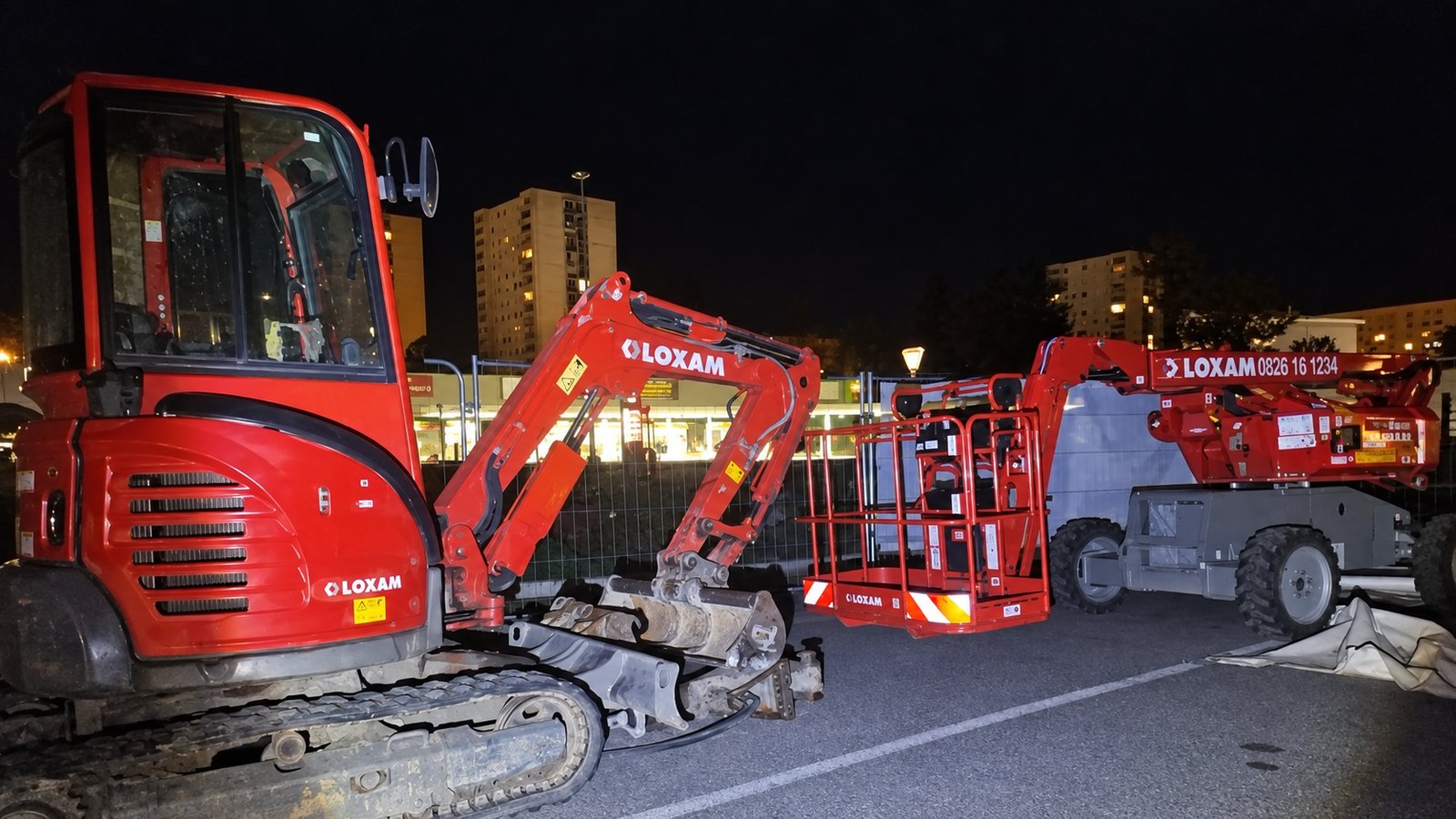 Mini-pelle et nacelle stationnées de nuit sur le parking du chantier d'Échirolles